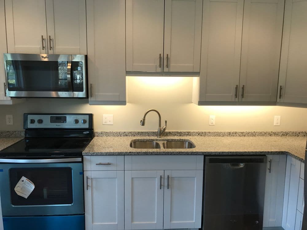 Modern kitchen with stainless steel appliances, granite countertops, and under-cabinet lighting.