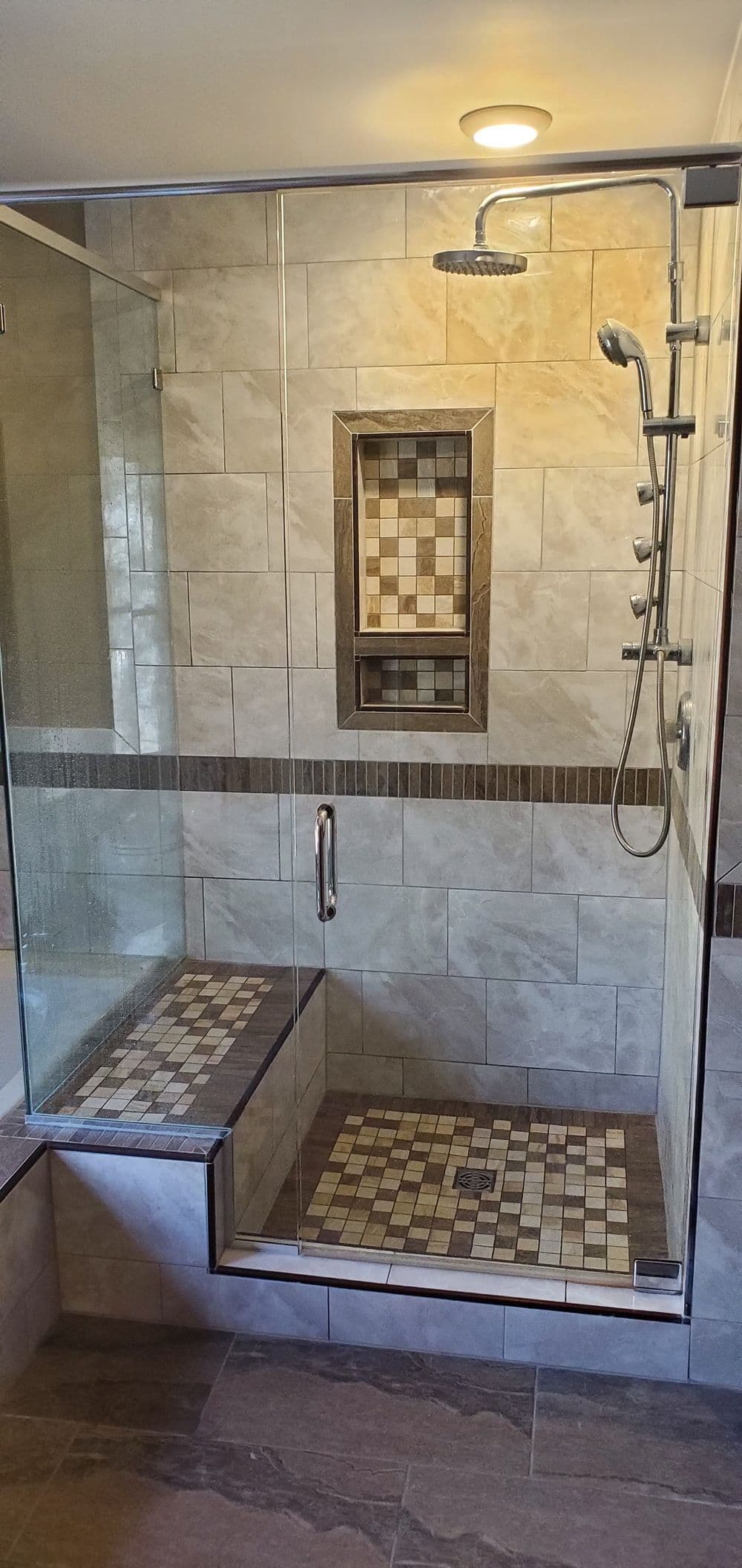 Modern walk-in shower with glass enclosure, decorative tile design, and rainfall showerhead.