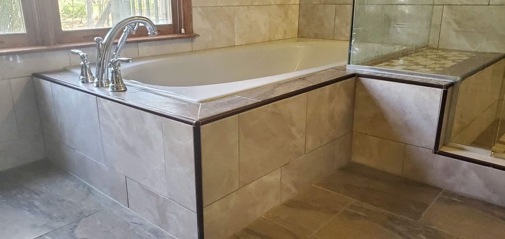 Modern bathroom featuring a sleek white bathtub, elegant faucets, and tiled surfaces.