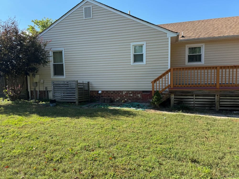 Exterior view of a single-story house with wooden deck and green lawn.